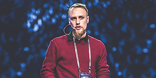 Graham Ashton spricht auf einer Bühne mit Headset