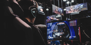 Computerspieler auf einer Messe vor einem Bildschirm.
